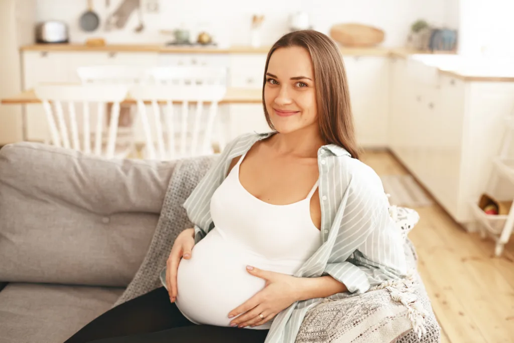 Mulher grávida sentada em um ambiente fechado.  A Idade Ideal para Engravidar