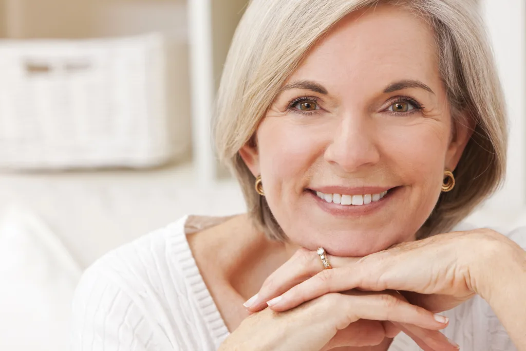 mulher de 50 anos sorrindo com a mão no queixo para ter uma boa vida aos 50